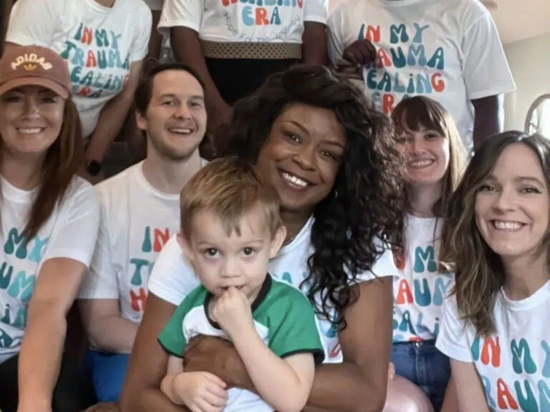 The Hope For The Journey Collective team on a staircase wearing matching In My Trauma Healing Era shirts