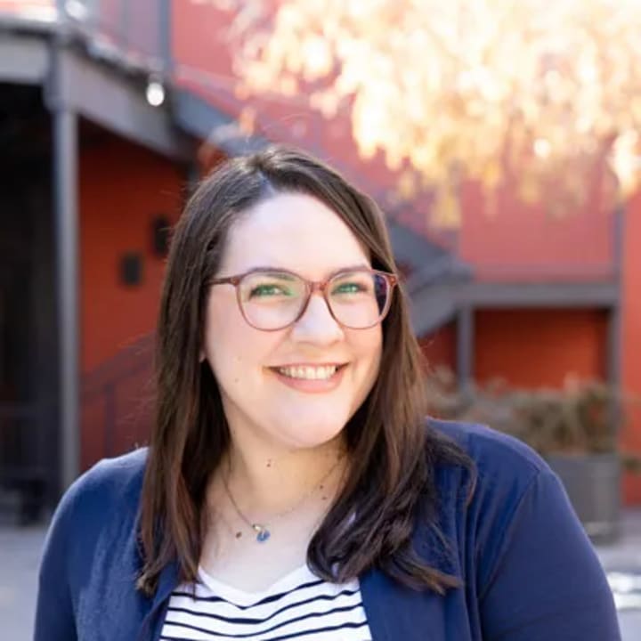 Maegan Woytek smiling outdoors in a striped shirt and navy cardigan