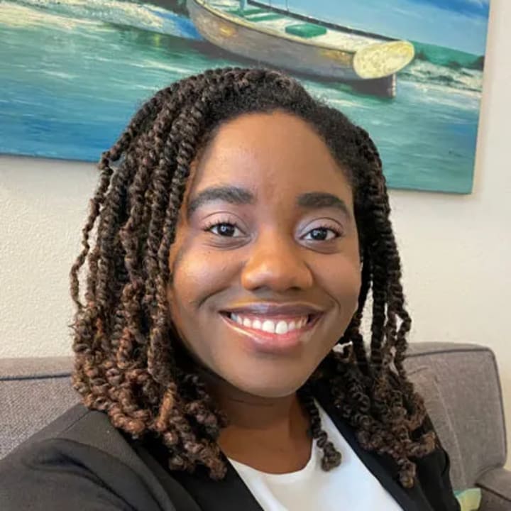 Shauna Onabajo smiling in a black blazer in a cozy office