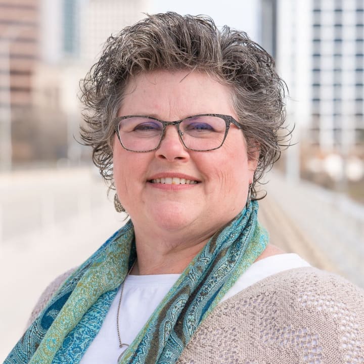 Heather Hammock smiling outdoors in glasses and a colorful scarf