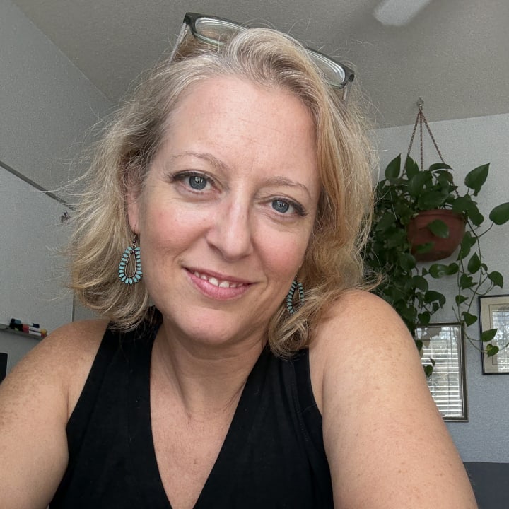 Traci W. Pirri smiling in a black top with turquoise earrings