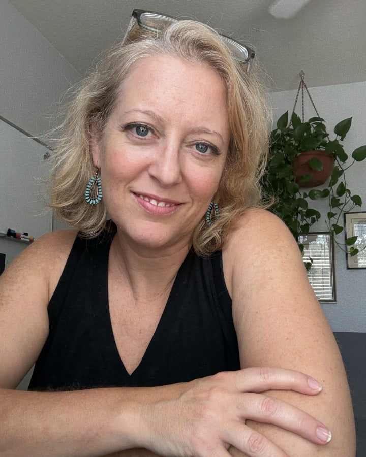 Traci W. Pirri smiling in a black top with turquoise earrings