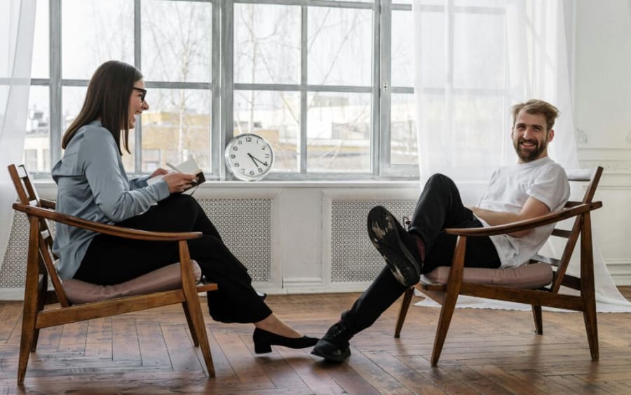 Two people mid-session in armchairs by a bright window