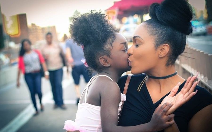A mother and daughter sharing a kiss outdoors