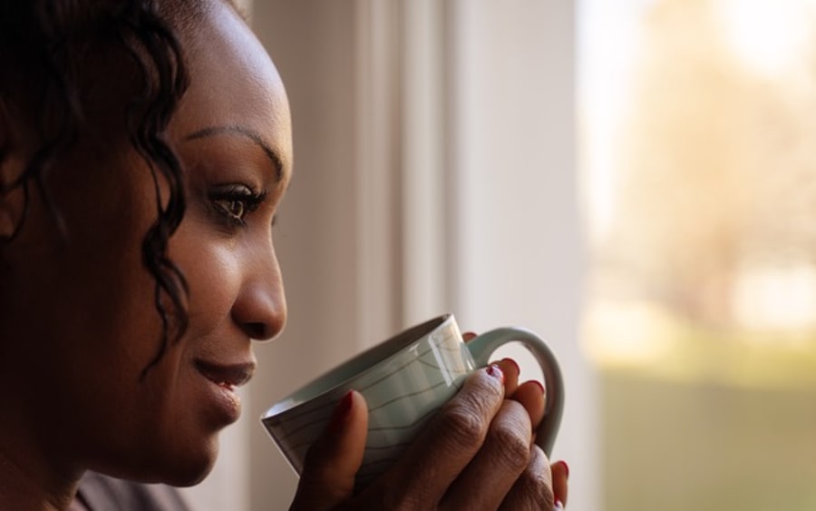 A woman holding a mug, looking out of a window