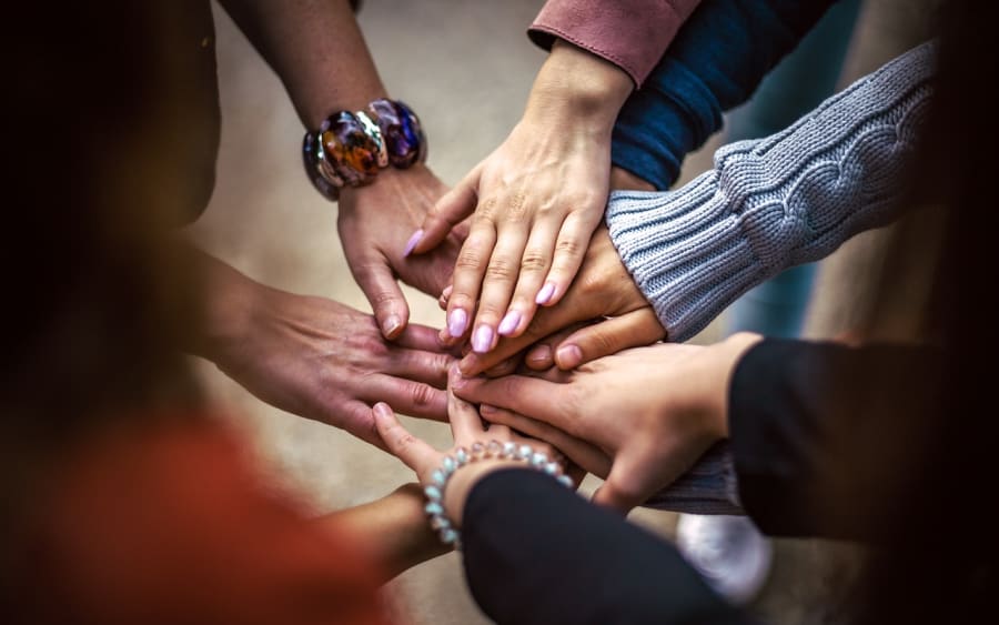 Several hands joined together in the middle of a circle