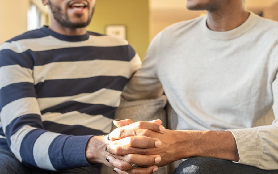 Two people on a couch, hands clasped, deep in conversation